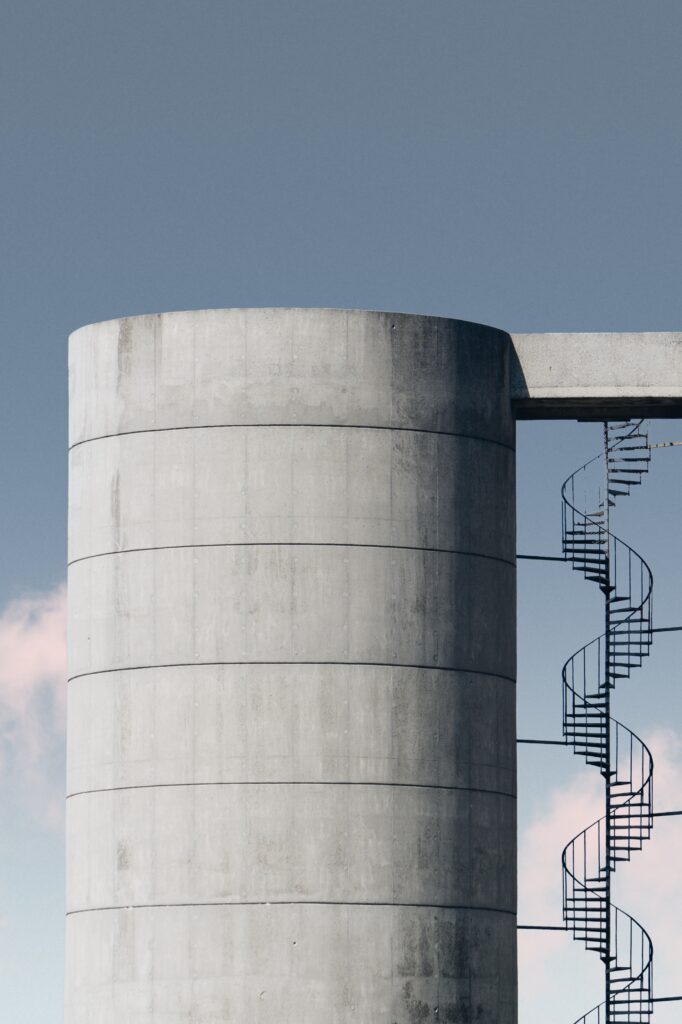 Vertical shot of a concrete structure with metal stairway under the blue sky
